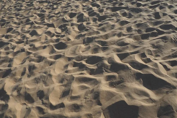 Песок при низком солнечном свете в золотой час. Пустой пляж, следы и вмятины на песке. Дюны Черного моря. Свободные осадочные породы, состоящие из зерен горного и минерального кварцевого диоксида кремния — стоковое фото
