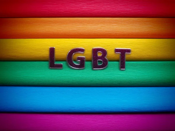 Afkorting LGBT, brief tekst. Paarse LGBT letters op de achtergrond van de regenboogvlag. Donker vignet. Een Rainbow Flag, de Pride Flag. LGBTQ-gemeenschapssymbool. — Stockfoto