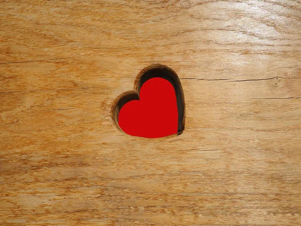 Heart carved in wooden wall texture. Postcard or blank for Valentines Day on September 14th. The heart is a symbol of love and passion. Carved red heart. The wooden surface is illuminated by the sun — Stock Photo, Image