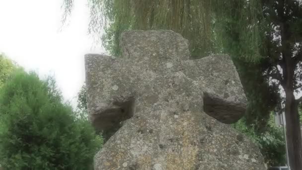 Vieja cruz de piedra en el cementerio por la tarde en el verano. Fondo borroso brumoso. Tema Halloween. Sremska Mitrovica, Serbia. Antigua lápida de la Cruz musgosa. Un misterioso lugar misterioso. El sauce se balancea — Vídeo de stock