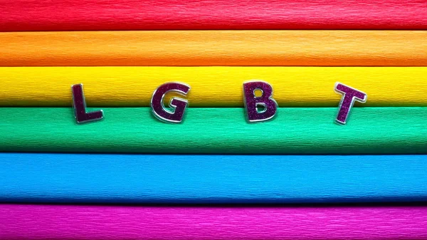 Συντομογραφία ΛΟΑΤ, γραπτό μήνυμα. Μωβ ΛΟΑΤ γράμματα στο φόντο της σημαίας του ουράνιου τόξου. Μια σημαία Ουράνιο Τόξο, η σημαία υπερηφάνειας. ΛΟΑΤΚΙ σύμβολο κοινότητας. EuroPride 2022 — Φωτογραφία Αρχείου