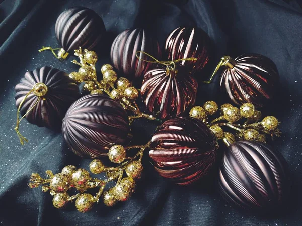 黒の背景に装飾、クリスマスの装飾や輝きを持つ新年とクリスマスのためのカード。茶色の光沢のある縞模様のボール、花と白い雪の結晶、果実と黄金の小枝 — ストック写真