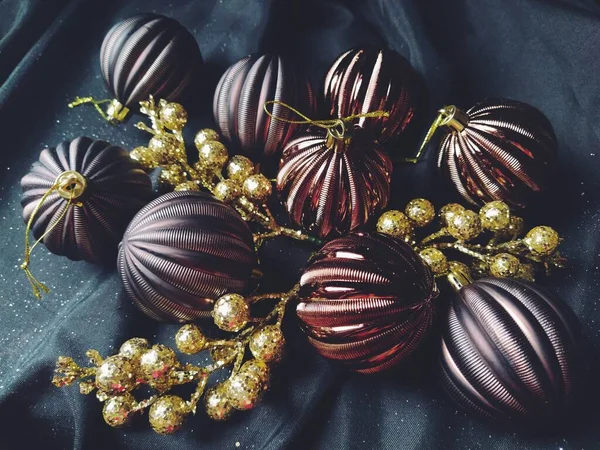 Karta na nowy rok i Boże Narodzenie z dekoracjami, świąteczne dekoracje i musujące na czarnym tle. Brązowe błyszczące kulki w paski, kwiaty i białe płatki śniegu, złote gałązki z jagodami — Zdjęcie stockowe