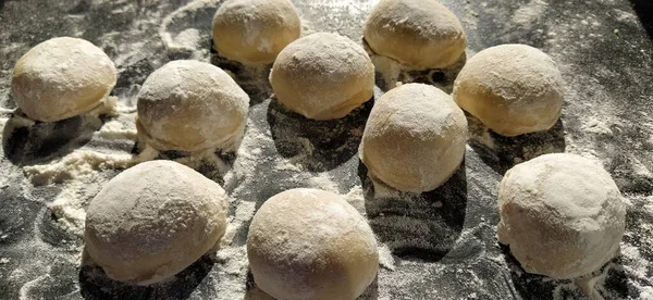 Bulat adonan roti manis untuk membuat kue atau roti jahe. Roti mentah atau pangsit dengan tepung yang tersebar di sekitar latar belakang hitam — Stok Foto