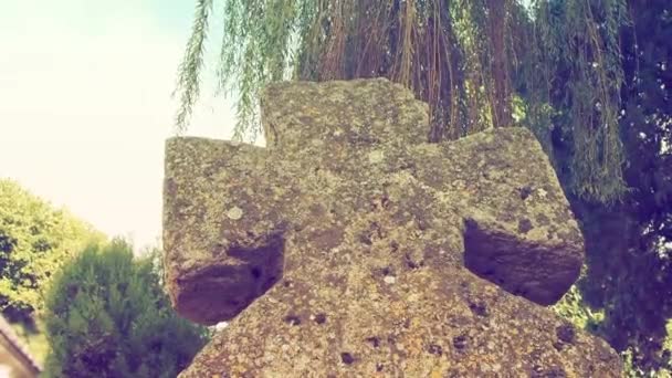 Velha cruz de pedra no cemitério durante o dia de verão. Foggy desfocado fundo. Tema de Halloween. Velho túmulo musgoso da Cruz. Um lugar misterioso. O salgueiro balança. Estilo retro e vintage. — Vídeo de Stock