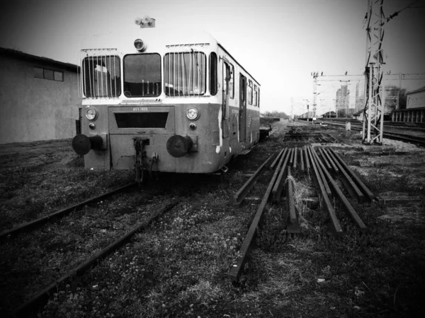 Retro treinwagon. Vintage locomotief gemaakt in Joegoslavië. Sremska Mitrovica, Zwart-wit monochrome fotografie. De metalen carrosserie van een spoorwegvoertuig. Roestige rails. Spoorwegstation. Donkere vignetten — Stockfoto