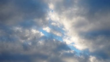 Pofuduk bulutlar parlak mavi bir gökyüzünde sürükleniyor güneş ışığı içinden geçerken, güzel bir ışık ve gölge gösterisi yaratıyor. Sahne, doğayı, huzuru ve güzelliği yakalar..