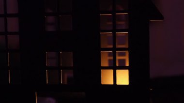 Mum ışığı, karanlık bir kalede titreyen gölgeler oluşturur. Ürkütücü siluetleri ortaya çıkaran pencereleri aydınlatır. Atmosfer, gece çökerken gizem ve korkuyla doludur. Cadılar Bayramı.