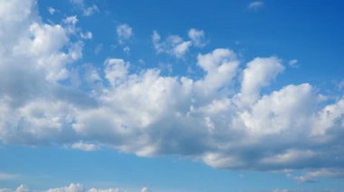 Yumuşak beyaz bulutlar parlak bir öğleden sonra açık mavi gökyüzünde tembelce sürüklenirler. Barışçıl atmosfer kırsal kesimin güzelliğini artırır. Doğa sakinliğini sergiler. Dramatik gökyüzü.