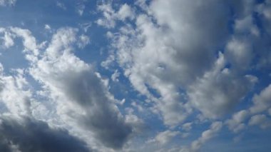 Parlak mavi gökyüzünde süzülen tüylü bulutların zaman akışı güneş ışığı ve gölgenin güzel bir görüntüsünü oluşturur. Sahne doğa güzelliğini yakalar. Hızlı hareket