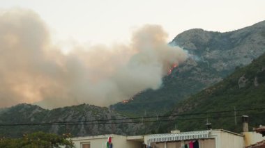 Chan, Montenegro, August 11 2025: Fire in mountains over village. Natural and anthropogenic forest fires. Danger of fire. Coniferous forest is burning. Hot dry weather on Adriatic coast Mediterranean