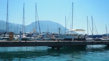 Bar, Montenegro 10 August 2025: Enjoy peaceful view of beautiful harbor. Witness boats gently bobbing in calm waters under clear blue sky, surrounded by majestic mountains. Water tourist excursion.