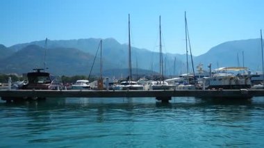 Bar, Montenegro 10 August 2025: Enjoy peaceful view of beautiful harbor. Witness boats gently bobbing in calm waters under clear blue sky, surrounded by majestic mountains. Water tourist excursion.
