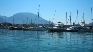Bar, Montenegro 10 August 2025: Enjoy peaceful view of beautiful harbor. Witness boats gently bobbing in calm waters under clear blue sky, surrounded by majestic mountains. Water tourist excursion.
