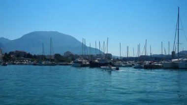 Bar, Montenegro 10 August 2025: Enjoy peaceful view of beautiful harbor. Witness boats gently bobbing in calm waters under clear blue sky, surrounded by majestic mountains. Water tourist excursion.