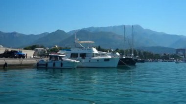 Bar, Montenegro 10 August 2025: Enjoy peaceful view of beautiful harbor. Witness boats gently bobbing in calm waters under clear blue sky, surrounded by majestic mountains. Water tourist excursion.