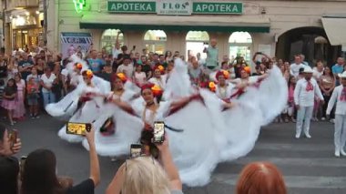 Sremska Mitrovica, Sırbistan, 12 Ağustos 2025: Beyaz ulusal Meksika kostümlü genç güzel dansçılar, erkekler ve kadınlar geleneksel Meksika halk dansları yapıyorlar. Seyircilerin önünde bir anda ortaya çıkıverdi..