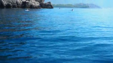 Sutomore, Montenegro 10 August 2025: Boat coastline tour. Sail Adriatic Sea dramatic cliffs and coastal forest. Devachen beach, Zagradje. Red cliffs. Uvala Strbina. Tourists on kayaks, kayaking sport.