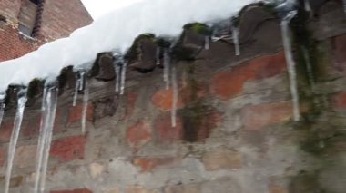 Buz saçakları karla kaplı çatıdan sarkıyor. Parlak formlar, eski tuğla duvarın kırsal çekiciliğiyle çelişiyor. Kış güzelliğine ve doğanın hassas dengesine tanık olun. Damlayan ya da akan suyun donması.