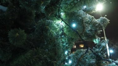 Noel ağacı ampuller ve çelenklerle parlar. Süslü Noel ağacı, Noel baloları. Kasaba meydanı şenlikli bir gecede. Şehirdeki aydınlanma. Kış havası. Yüksek kalite 4k görüntü