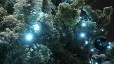 Noel ağacı ampuller ve çelenklerle parlar. Süslü Noel ağacı, Noel baloları. Kasaba meydanı şenlikli bir gecede. Şehirdeki aydınlanma. Kış havası. Yüksek kalite 4k görüntü