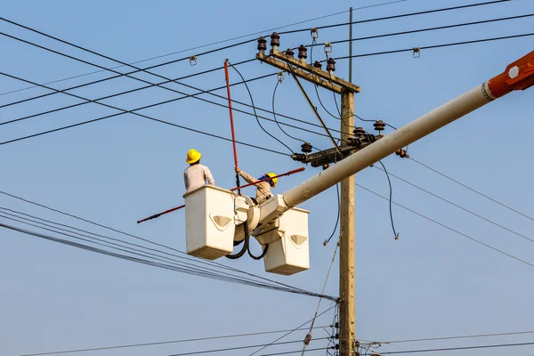 Elektricien werknemer op het werk op hoogspanning post klimmen — Stockfoto