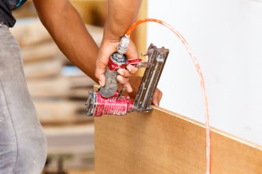 Marangoz yeni mobilya yapmak için havalı silah kullanır.