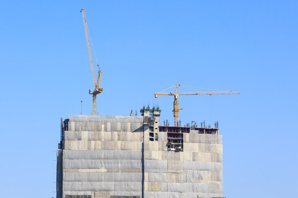 Building crane and construction site under blue sky 