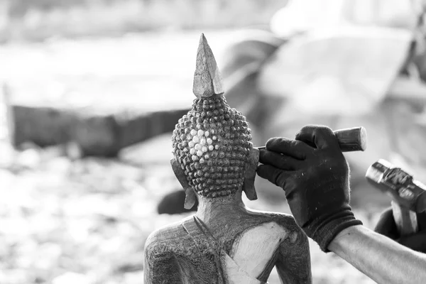 Hand of carver carving wood in black and white color tone