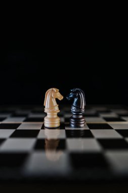 İki at bir satranç tahtasının üzerinde karşı karşıya, koyu bir tarzda. Irklar arası aşk kavramı. Dikey