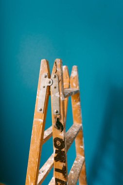 Mavi arka planda boya lekeli eski, ahşap bir merdiven. Ressam.