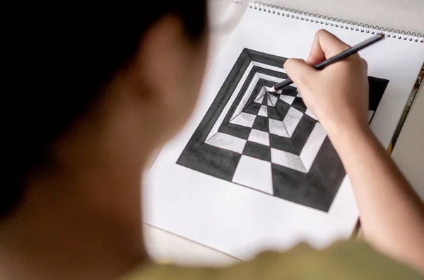 A woman making a perspective drawing with black and white fixings holding a pencil in her hand.