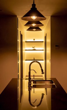 Siyah mermer çubuklu ve paslanmaz çelik bulaşık makineli güzel aydınlatılmış bir mutfak..