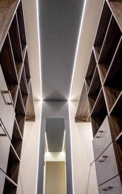 Siyah raflı ahşap dolap ve beyaz duvarlı çekmeceler ve ortasında bir ayna..