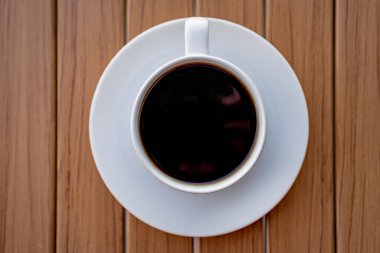 Ahşap bir masanın üzerinde nefis beyaz bir fincan kahve..