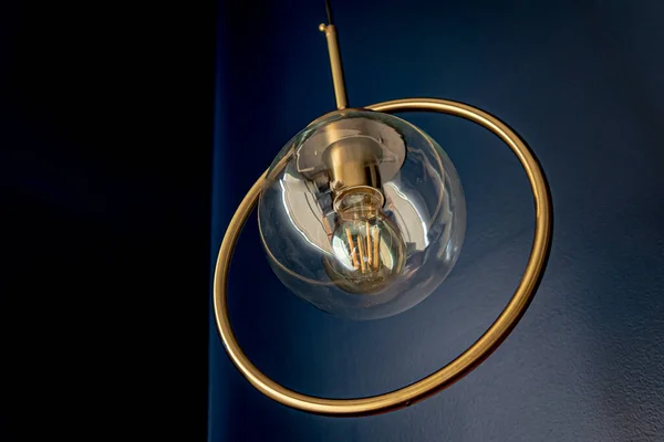 Beautiful pendant lamps for interiors adorned with a golden ring and blue background.