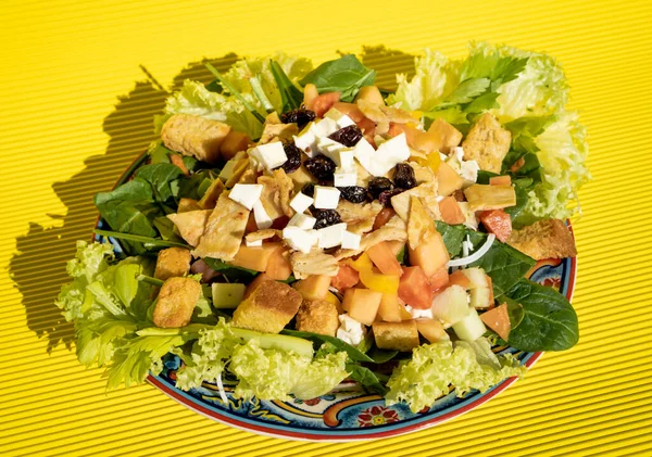 上にクルトン レタス トマト マグロ チーズと果物を乗せた絶妙な健康的なサラダ 黄色のテーブルの上に手作りのプレート上に — ストック写真
