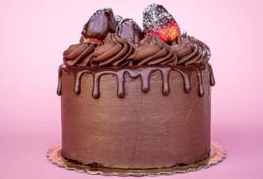 Çikolata kaplı ve üstünde çilek ve pembe arka planla süslenmiş lezzetli Sevgililer Günü pastası..