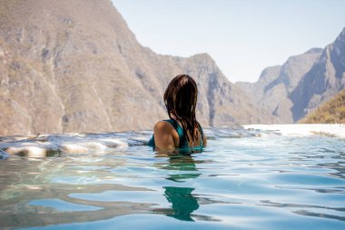Mavi mayo giymiş güzel bir kadın Tolantongo Meksika 'da büyük bir mağaranın önünde suyun içinde..
