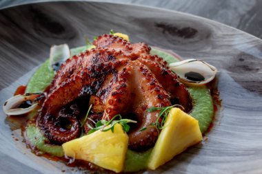 Lezzetli Meksika usulü mangal kömürü yeşil soslu ahtapot dokunaçları ve ahşap bir tabakta ananas..