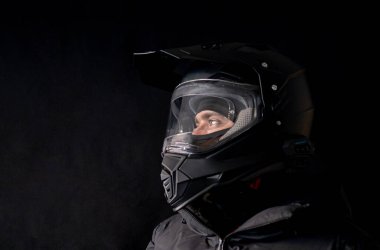 Motosikletli siyah çift amaçlı motosiklet kaskı takıyor. Siyah bir ceketi ve yakın plan konsepti var..