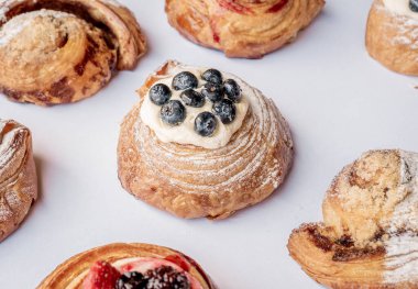 Lezzetli limonlu kruvasan hamur rolü, beyaz bir masanın üstünde böğürtlenler ve yakın çekim konseptinde aromalı roller..