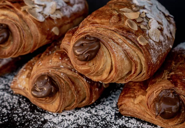 Exquisite French-style almond chocolates filled with chocolate on a black table decorated with sugar in a close up concept.