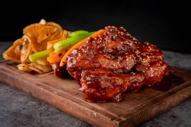 Kırsal bir panoda havuç, kereviz ve cips ile servis edilen nefis barbekü kanatları..