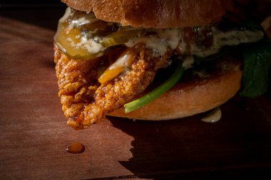 Ekmek, ıspanak, turşu ve panoya sarılmış çıtır tavuk burger..