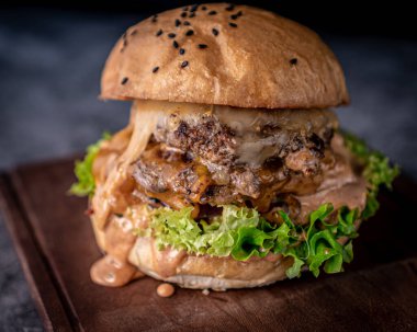 Lezzetli çift köfte, zanaatkar çörek, pastırma, Jack peyniri, çedar peyniri ve turşu sosu..