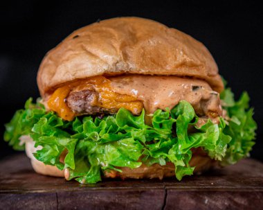 Köy tarzı bir panoda servis edilen lezzetli, klasik hamburger, biftek, pastırma, soğan ve turşu soslu..