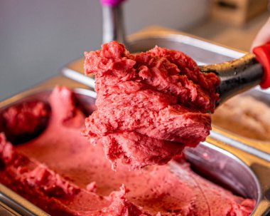 Bir üste lezzetli çilekli dondurma ve bir kaşıkla tutulmuş..