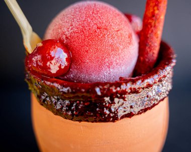 Tekila, çilekli kar, kırmızı biber tozu ve siyah arkaplanlı geleneksel Meksika şekeri ile nefis bir kantarito..