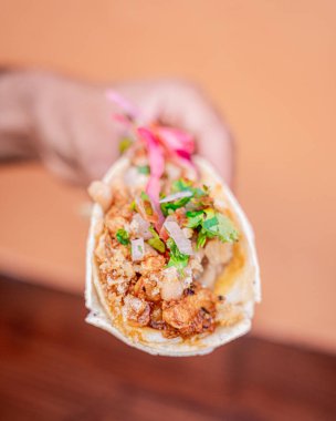 Lezzetli Meksika usulü chicharron ve Carnitas taco domates, soğan, kişniş ve mor soğanlı, tek elle tutulan.